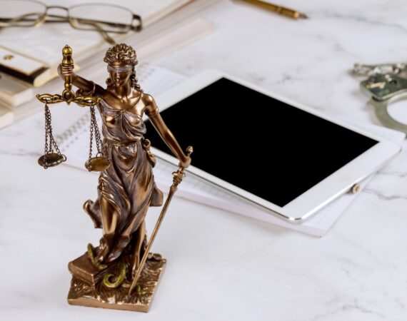 Lawyer Statue of Justice with scales lawyers symbols office working on a digital tablet