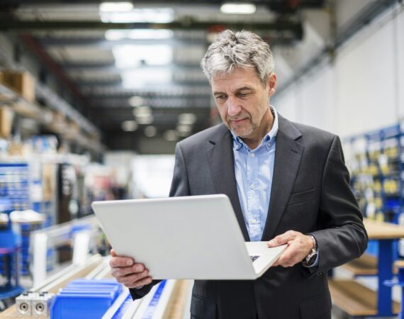 Businessman using laptop in production hall