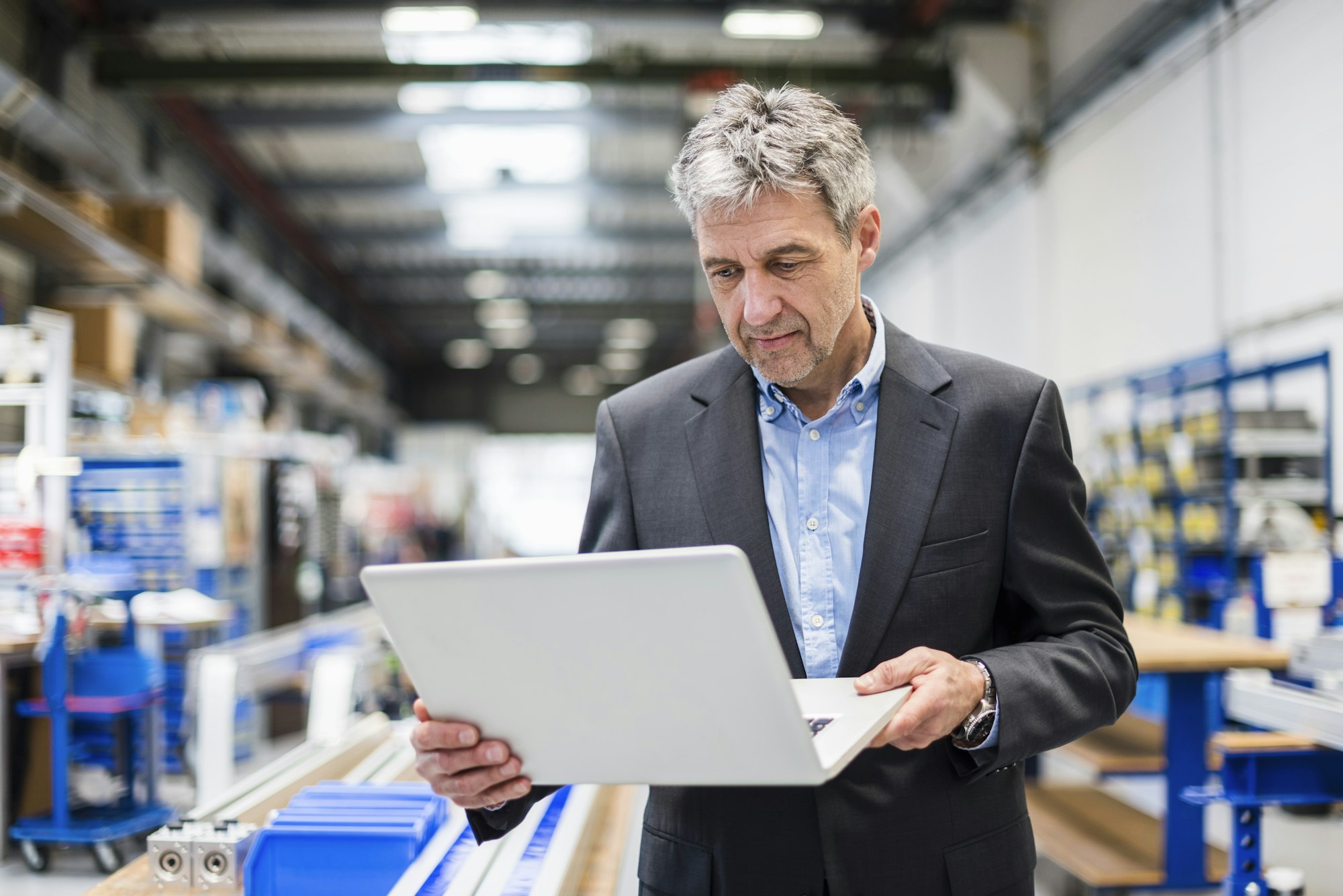 Businessman using laptop in production hall