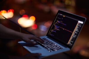 He knows his way around any network. Shot of an unrecognisable hacker using a laptop in the dark.