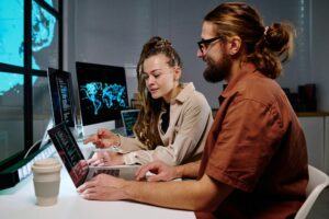 Young female programmer pointing at laptop screen with coded data