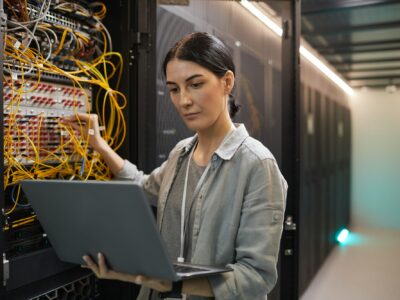 Female Network Technician Inspecting Servers in Data Center