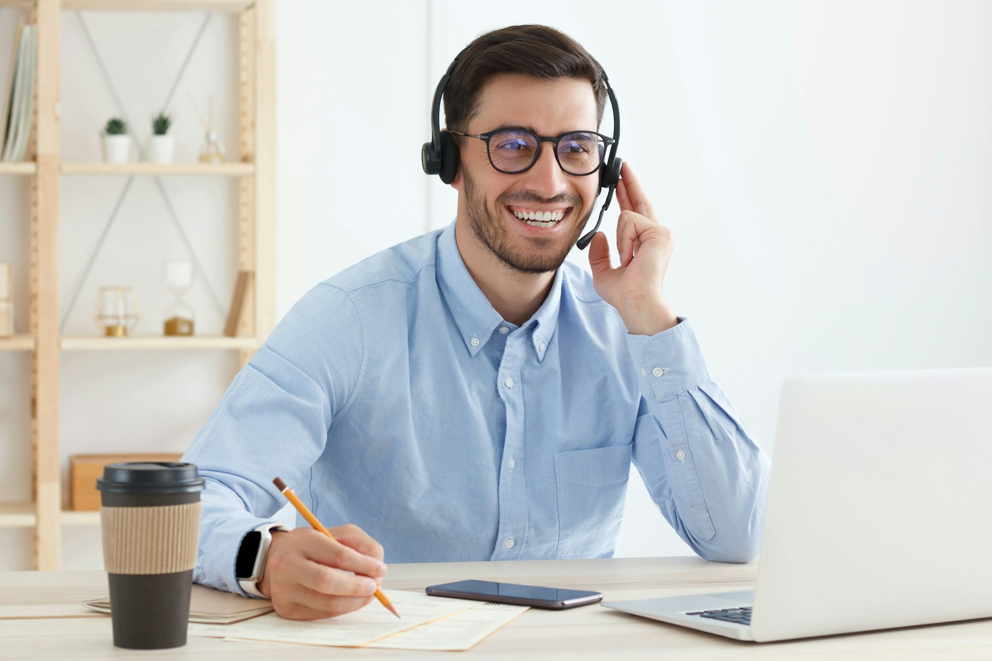 Smiling customer support service operator with hands-free headset working in office